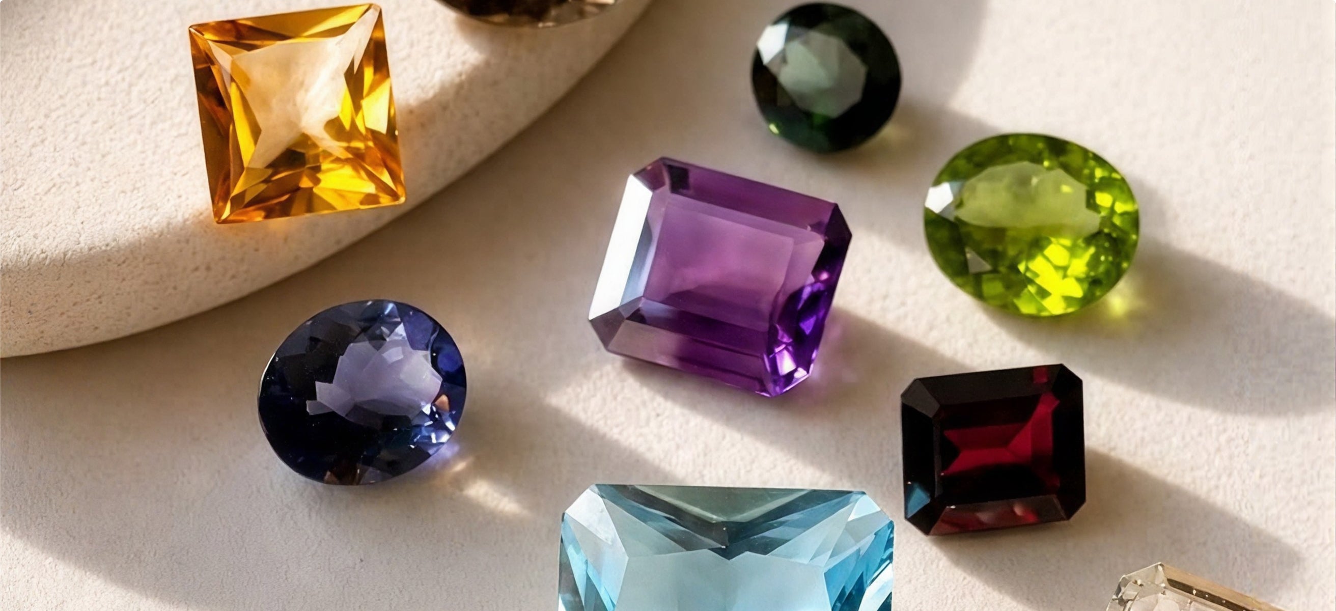 Coloured gemstones of different cuts on a cream surface