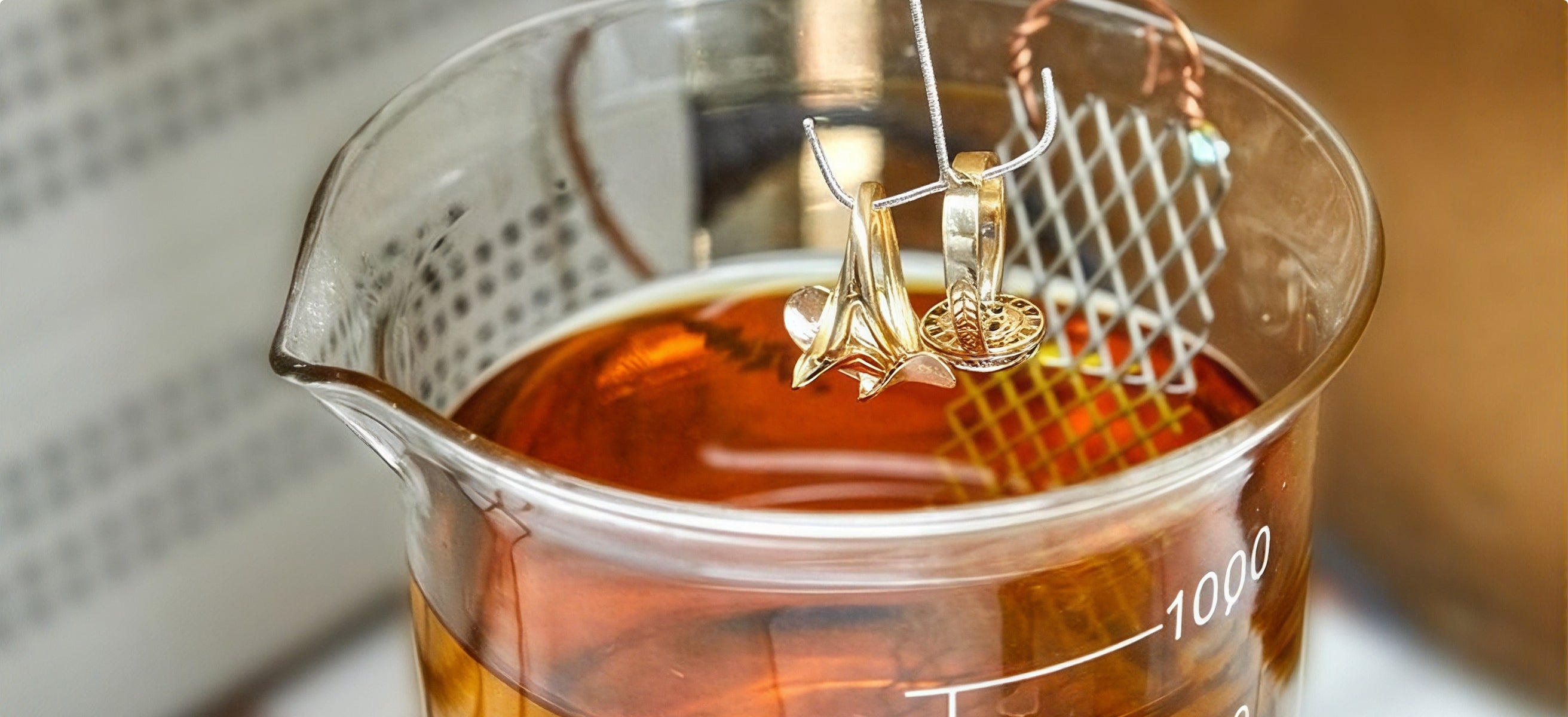 Jewellery suspended in a beaker of plating solution