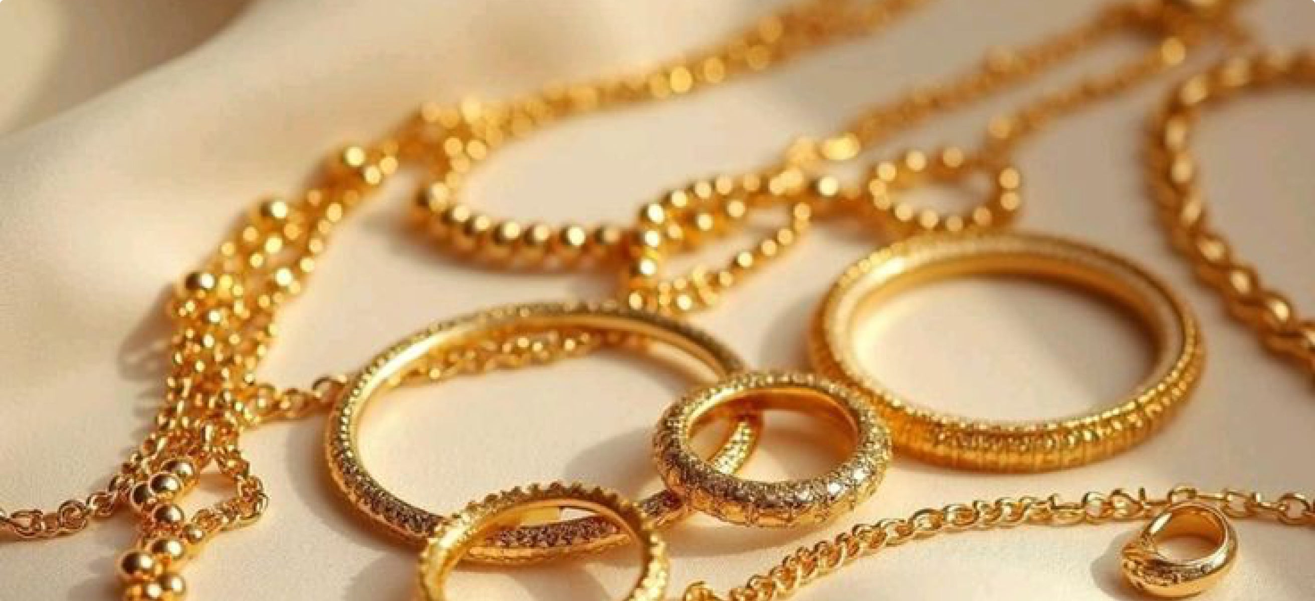 Gold chains and rings laid out on cream fabric